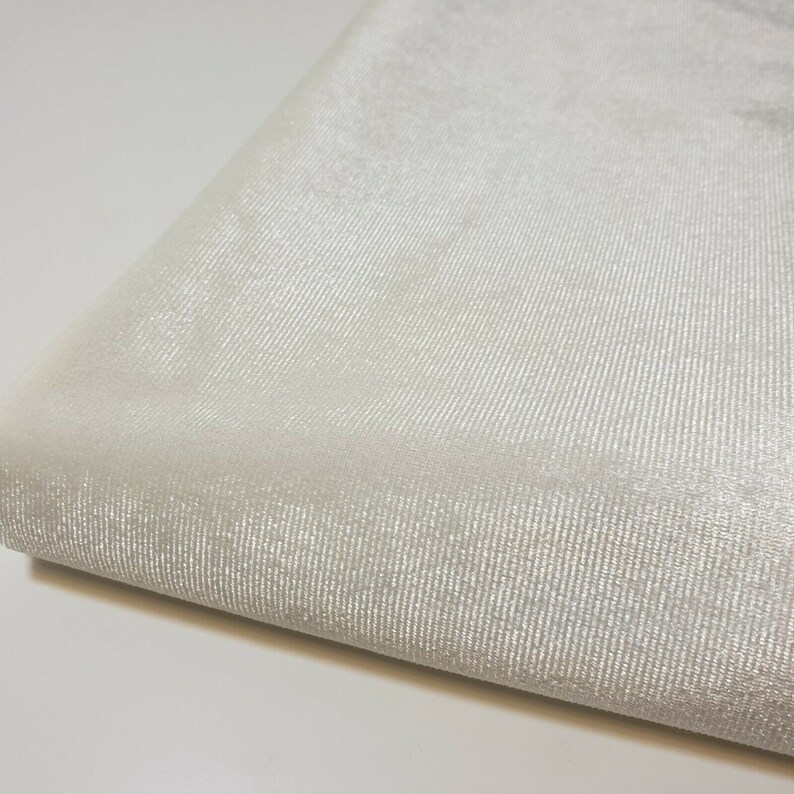 May include: White sheer fabric with a subtle shimmer. The fabric has a fine, woven texture.