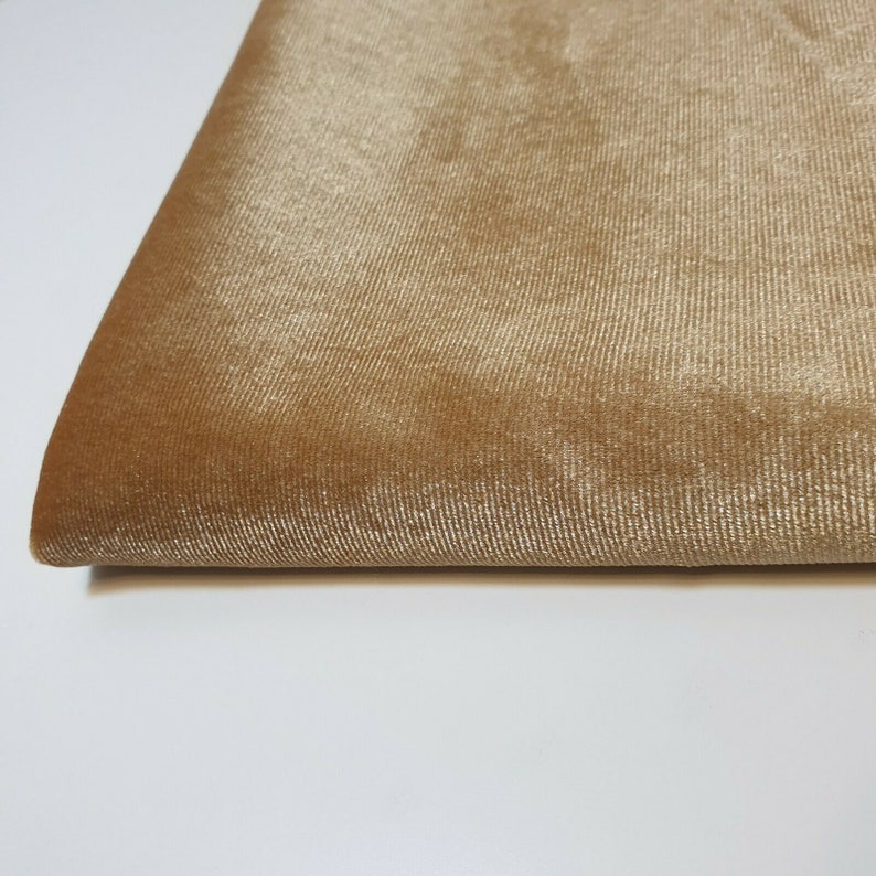 May include: A close-up of a piece of fabric in a light brown color. The fabric has a soft, velvety texture.