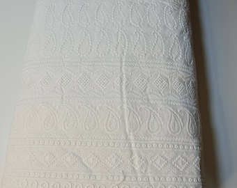 May include: White cotton fabric with an embroidered paisley pattern. The fabric has a delicate lace trim.