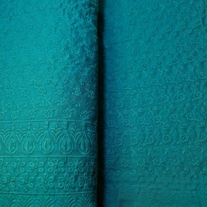 May include: Teal fabric with an embroidered floral pattern. The fabric has a subtle ombre effect, with a darker shade at the bottom and a lighter shade at the top.