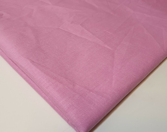 Peut inclure: Un gros plan sur un tissu doux et rose à la texture lisse. Le tissu est plié dans un coin, montrant les bords.