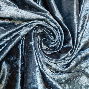 Può includere: Primo piano di un morbido tessuto di velluto blu con un motivo a spirale e texture.