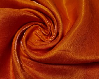 May include: Close-up of a smooth, orange fabric with a swirling pattern. The fabric is soft and luxurious, with a subtle sheen.