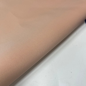 Peut inclure: Gros plan sur un tissu de couleur pêche avec une surface lisse et légèrement texturée.
