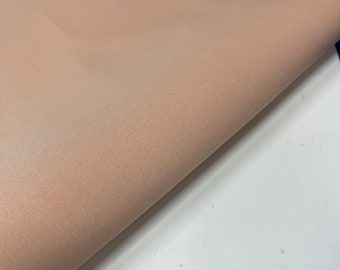 May include: A close-up of a peach-colored fabric with a smooth, slightly textured surface.