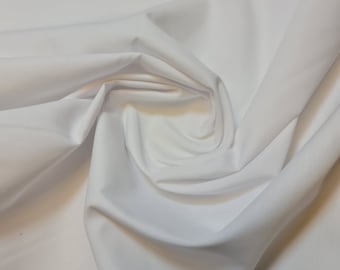 May include: White fabric with a smooth, silky texture. The fabric is folded and draped, showcasing its soft and flowing nature.
