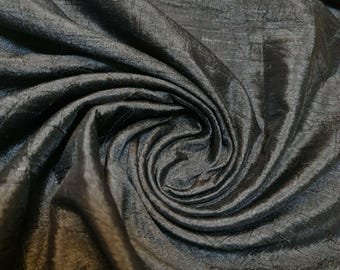 May include: Close-up of a black silk fabric with a subtle sheen. The fabric is draped and folded, creating a soft, flowing texture.