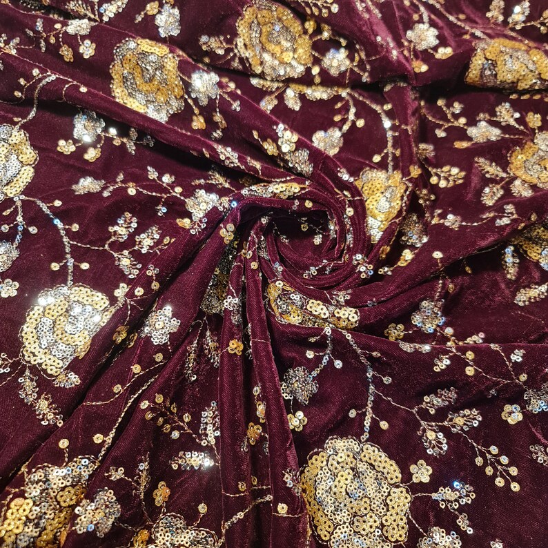 May include: Burgundy velvet fabric with gold and silver sequins in a floral pattern.