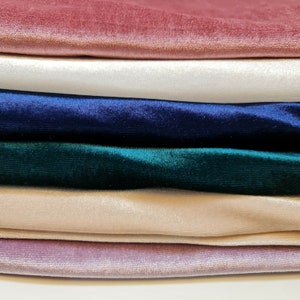 May include: Stack of six velvet fabric swatches in various colors, including pink, white, navy blue, green, beige, and mauve.