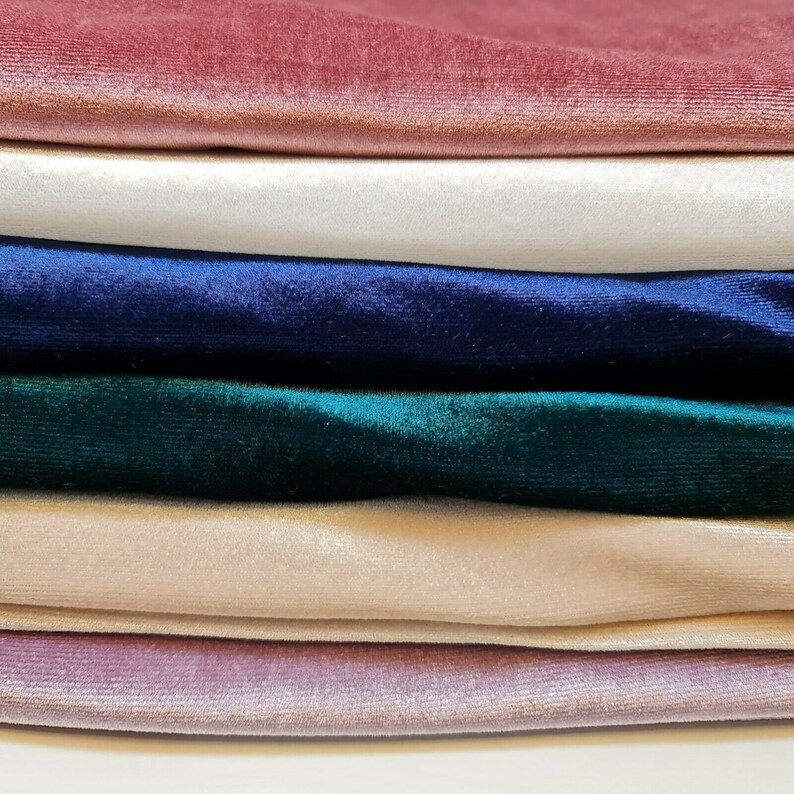 May include: Stack of six velvet fabric swatches in various colors, including pink, white, navy blue, green, beige, and mauve.