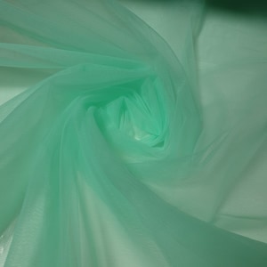 May include: A piece of soft, light green tulle fabric. The fabric is sheer and delicate, with a slightly crinkled texture.