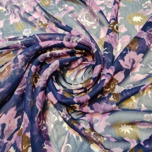 Puede incluir: Primer plano de una tela transparente con estampado floral en tonos morados, marrones y azules.