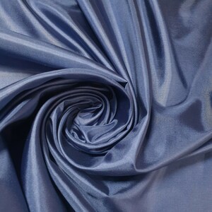 Könnte beinhalten: Nahaufnahme eines glatten, blauen Stoffes mit einem wirbelnden Muster. Der Stoff ist weich und luxuriös, mit einem dezenten Glanz.