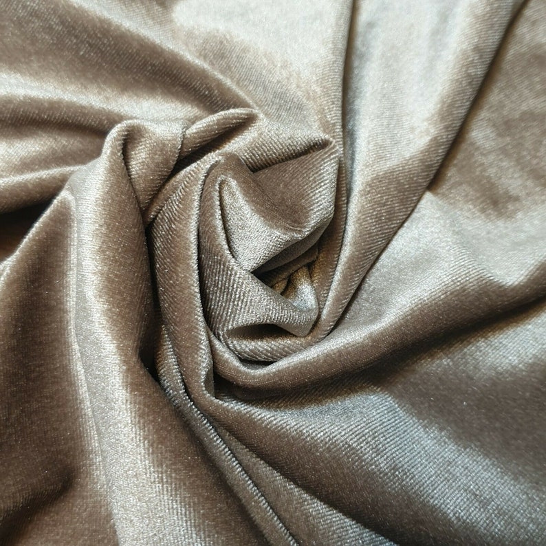 May include: Close-up of a soft, smooth, gray velvet fabric with a subtle sheen. The fabric is draped and folded, creating a luxurious and elegant texture.