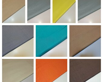 May include: A collection of fabric swatches in various colors, including beige, gray, yellow, teal, orange, and brown. The fabric is folded in half and displayed on a white surface.