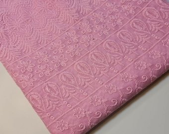 May include: Pink cotton fabric with embroidered floral and paisley patterns. The fabric has a delicate, feminine look and would be perfect for a variety of sewing projects.
