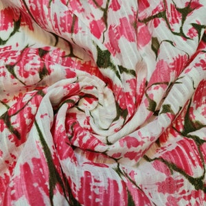 Può includere: Tessuto bianco con stampa floreale rosa e verde. Il tessuto è trasparente e ha una texture leggermente stropicciata.