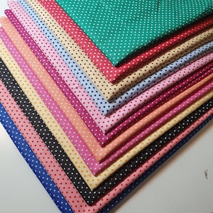 May include: A stack of fabric with white polka dots on different colored backgrounds. The colors include green, red, yellow, orange, pink, blue, and black.