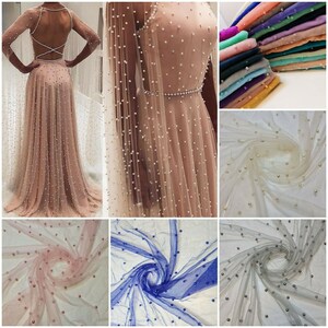 May include: A collection of sheer fabric with pearl embellishments in various colours, including ivory, pink, blue, and grey. The fabric is shown draped and folded, showcasing the pearl details.