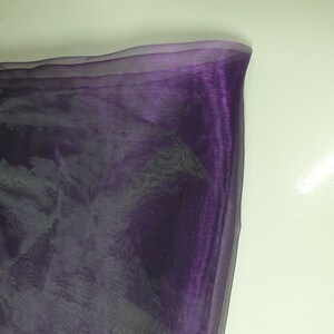 May include: Purple sheer fabric with a slight iridescent sheen. The fabric is translucent and has a soft, flowing texture.