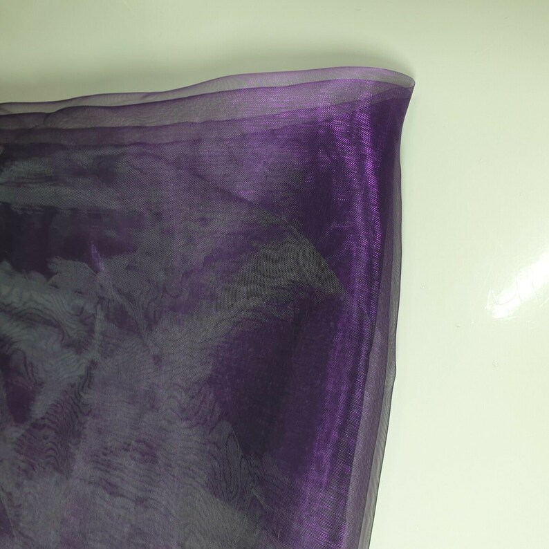 May include: Purple sheer fabric with a slight iridescent sheen. The fabric is translucent and has a soft, flowing texture.