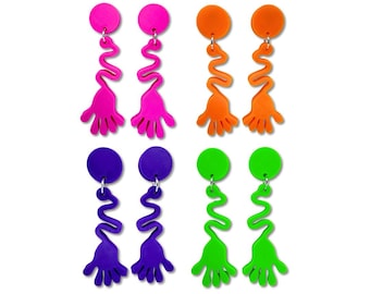 May include: A set of four pairs of colorful, abstract earrings. Each pair features a round stud in pink, orange, purple, or green, connected to a squiggly line and a hand-shaped charm. The earrings are a vibrant accessory.