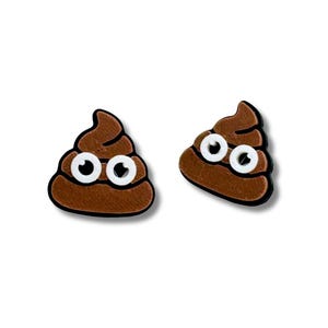 May include: A pair of brown poop emoji earrings with white eyes. The earrings are made of a soft, flexible material and are perfect for adding a touch of humor to any outfit.