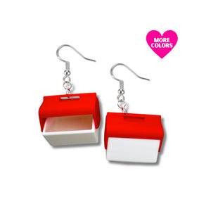 Könnte beinhalten: Ein Paar ausgefallene Ohrringe mit einem rot-weißen Design, das einem kleinen Behälter ähnelt. Die Ohrringe haben silberfarbene Haken und eine pinkfarbene herzförmige Grafik mit dem Text "MORE COLORS".