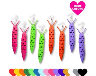 May include: A collection of colorful, segmented worm-shaped earrings in various colors, including pink, green, orange, and purple. The earrings have silver hooks and are displayed on a white background. A pink heart with the text "MORE COLORS" is also present.