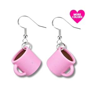 May include: A pair of pink coffee mug earrings with silver hooks. The mugs are small and have a brown interior.