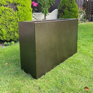 May include: A large, rectangular planter made of brown concrete. The planter is sitting on a green lawn.