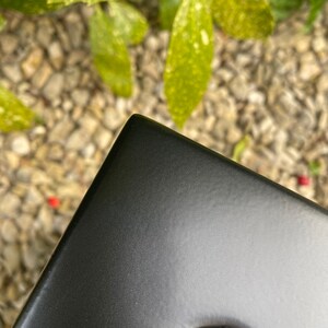May include: Close-up of a black metal corner of a chair or table. The metal has a smooth, slightly textured finish.