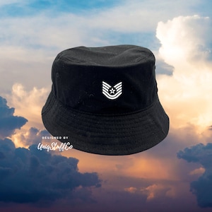 Peut inclure: Un chapeau bob noir avec un motif étoile et rayures brodé en blanc. Le chapeau a une visière plate et une couronne légèrement incurvée. Le texte "Designed by UniqStuffCo" est imprimé sur le chapeau.