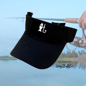 May include: Black visor with a white fish and hook graphic. The visor is designed by UniqStuffCo.