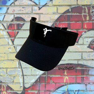 Könnte beinhalten: Schwarzer Visier mit einer weißen Silhouette einer Person, die eine Yoga-Pose auf der Vorderseite macht. Der Text "DESIGNED BY UniqStuffCo" ist auf der Seite des Visiers aufgedruckt.
