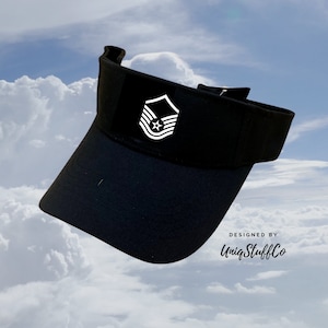 Puede incluir: Visera negra con un parche blanco de insignia de rango de la Fuerza Aérea. El parche muestra una estrella y tres galones. La visera tiene el texto "DESIGNED BY UniqStuffCo" impreso en el lateral.