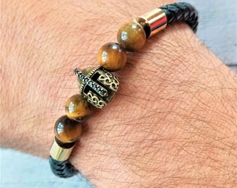 Braided black leather bracelet for Men with tiger's eye rock balls and stainless steel charms, centerpiece of the Spartan warrior helmet.