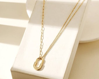 May include: A gold chain necklace with a small, oval-shaped pendant. The pendant is set with small, clear stones and has a lock-like design.