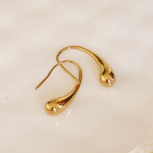 May include: A pair of gold teardrop shaped earrings. The earrings are made of a smooth, shiny metal.