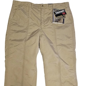 May include: Beige pants with a zipper on the side of each leg. The pants have a label that says "Thinsulate 3M" on the right side.
