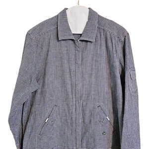 May include: A navy and white checkered jacket with a full zipper closure, two front pockets, and a small pocket on the right sleeve. The jacket is hanging on a white hanger against a white background.