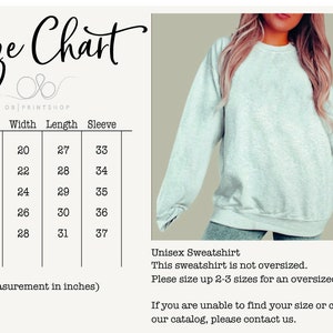 May include: A light gray unisex sweatshirt with a size chart and text. The size chart shows measurements in inches, with sizes ranging from S to XXL. The text states the sweatshirt is not oversized and suggests sizing up for a looser fit.