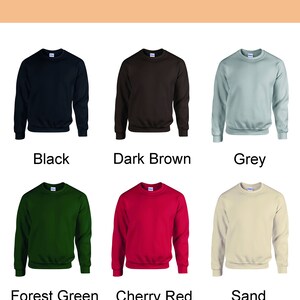 Op de afbeelding: Afbeelding met zes crewneck sweatshirts in verschillende kleuren: zwart, donkerbruin, grijs, bosgroen, kersenrood en zand. De tekst "Sweatshirt Colour" staat bovenaan, met elke kleur eronder benoemd.