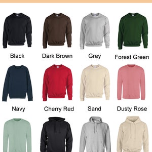 May include: A color chart displays various sweatshirt and hoodie colors. Colors include black, dark brown, grey, forest green, navy, cherry red, sand, dusty rose, dusty green, black hoodie, grey hoodie, and sand hoodie.