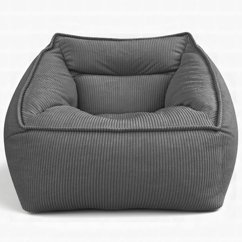 Puede incluir: Un sill&oacute;n de color gris oscuro con una textura de tela de pana suave y afelpada. El sill&oacute;n presenta una silueta redondeada de perfil bajo con un asiento profundo, laterales gruesos y acolchados, y un respaldo ancho con patr&oacute;n acanalado.