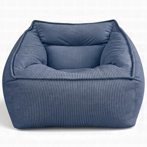 Puede incluir: Un sill&oacute;n tipo puf de pana azul con un dise&ntilde;o estructurado de forma cuadrada. La tela presenta una textura acanalada vertical distintiva en toda la superficie, incluyendo el respaldo, el asiento y los paneles laterales, creando un aspecto uniforme.