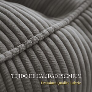 Puede incluir: Un primer plano de tela de pana gris con gruesas nervaduras verticales en relieve y una costura prominente que cruza diagonalmente la superficie. El texto TEJIDO DE CALIDAD PREMIUM y Premium Quality Fabric est&aacute; impreso en blanco y dorado.