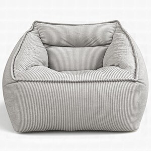 Puede incluir: Un sill&oacute;n de color gris claro tapizado en tela de pana texturizada. La silla presenta un dise&ntilde;o cuadrado de perfil bajo con un asiento profundo, reposabrazos integrados y un respaldo acolchado, todo cubierto con tela de canal&eacute; vertical.