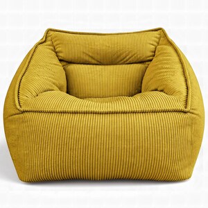 Puede incluir: Un sill&oacute;n de color amarillo mostaza confeccionado en tela de pana texturizada con detalles de acanalado vertical. El sill&oacute;n presenta un dise&ntilde;o cuadrado de perfil bajo con asiento profundo, reposabrazos integrados y respaldo acolchado con costuras visibles.