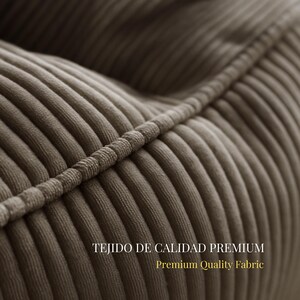 Puede incluir: Un primer plano de tela de pana color topo con crestas verticales distintivas y un detalle de costura ribeteada. El texto TEJIDO DE CALIDAD PREMIUM y Premium Quality Fabric est&aacute; impreso en letras blancas y doradas sobre la superficie.